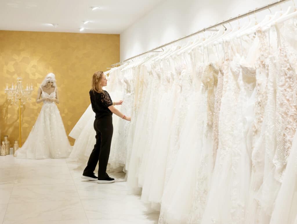 Bruidsadviseur tussen een grote collectie trouwjurken bij Koonings